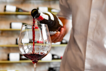 Waiter pouring red wine in glasses for wine on the table in restaurant