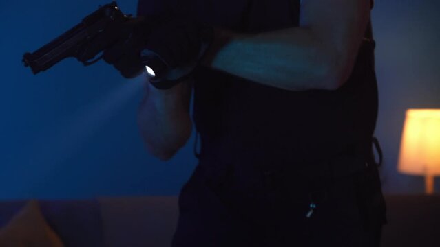 Video of a policeman keeping a burglar, intruder, offender at gunpoint in a dark room. Night, evening crime scene.