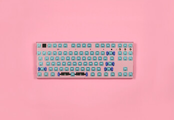 Pink mechanical keyboard without keycaps on the table on pink background