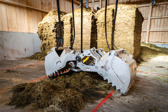 Moderner F&uuml;tterungsroboter,Kran zur Bef&uuml;llung im Futterlager greift nach Grassilage.