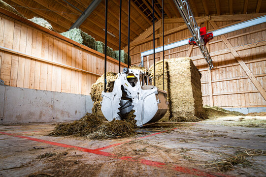 Moderner F&uuml;tterungsroboter,Kran zur Bef&uuml;llung im Futterlager greift nach Grassilage.