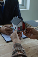 The real estate agent discusses the terms of the home purchase contract and asks the client to sign...