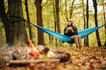 Charming woman resting in hammock among autumn forest