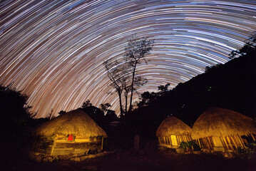 Star trails in the sky and village houses among the mountains