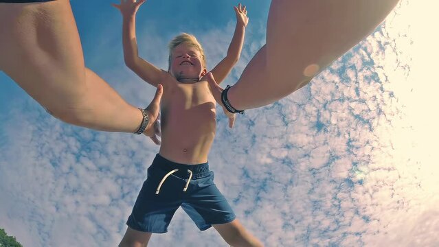 Slow motion POV video. Father throws son up when they play on the beach