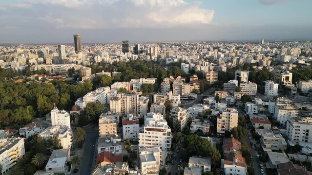 Establishing drone flight over apartment towers in residential neighborhood, flying towards offices and other buildings, skyline of city center of Nicosia (South)
