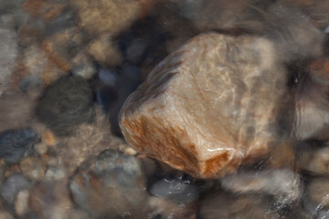 BEIGE COLORED STONES WET BY WATER ON THE SEASHORE