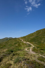 small path on top of a mountain with view towards alpine summits and sky