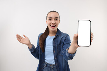 Surprised young woman showing smartphone in hand on white background