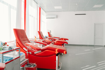 Red armchairs for sitting in donation center. Blood transfusion station for taking blood from donors