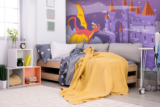 Kid's room interior with comfortable bed. Fairytale themed wallpapers with castle and dragon