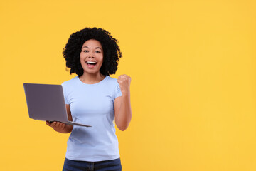 Emotional young woman with laptop on yellow background. Space for text