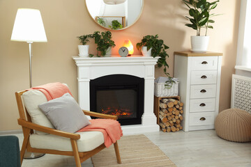 Stylish fireplace near comfortable armchair in cosy living room. Interior design