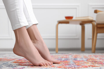 Woman on carpet with pattern at home, closeup. Space for text