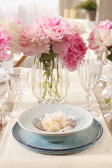 Stylish table setting with beautiful peonies and golden cutlery indoors