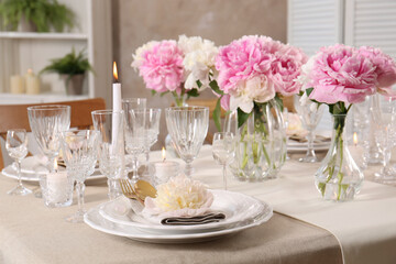 Fototapeta na wymiar Stylish table setting with beautiful peonies and burning candles indoors