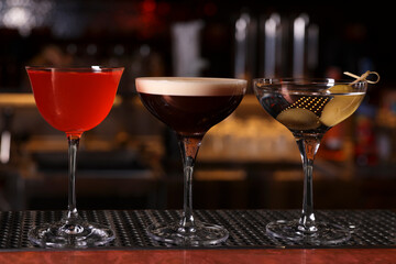 Glasses of different Martini cocktails on bar counter