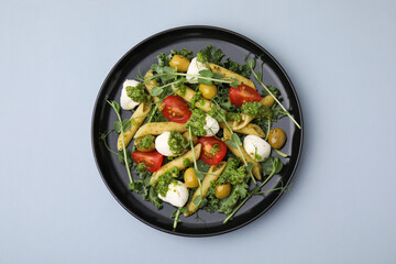Delicious pesto pasta salad on light grey table, top view