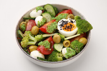 Delicious salad with pesto sauce in bowl on beige table, closeup