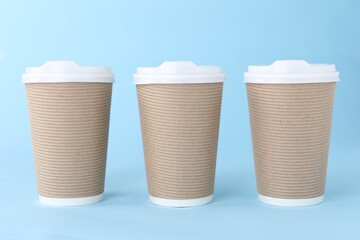 Paper cups with white lids on light blue background. Coffee to go