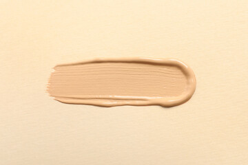 Smear of skin foundation on beige background, top view