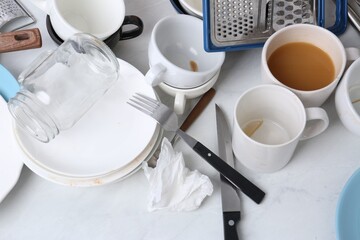 Many dirty utensils and dishware on countertop in messy kitchen, above view