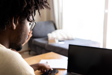 Black guy with afro hair working from home with the laptop