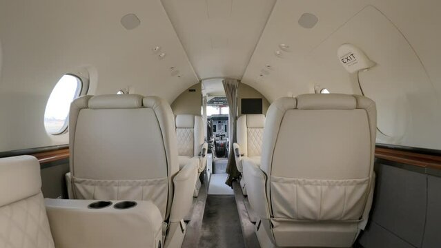 Tail section of private jet revealing view on luxurious vip salon with bright leather seats and portholes. Interior of business plane with best conditions for comfy flight