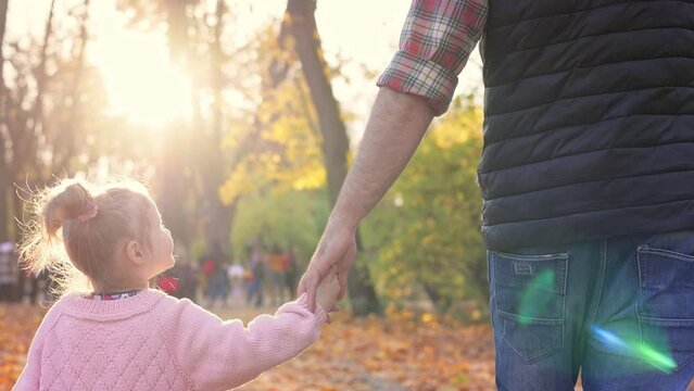 Happy family. Father and daughter walking in autumn park. Cute kid and dad having fun, enjoy spending time together. Happy carefree childhood. Close up back view.