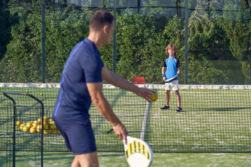 Trainer with boy playing padel game