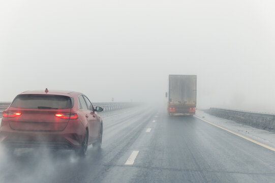 Driver POV on traffic on blue foggy misty rainy slush highway intercity road with low poor visibility on cold winter autumn morning. Seasonal bad rainy weather accident danger warning. car fog light