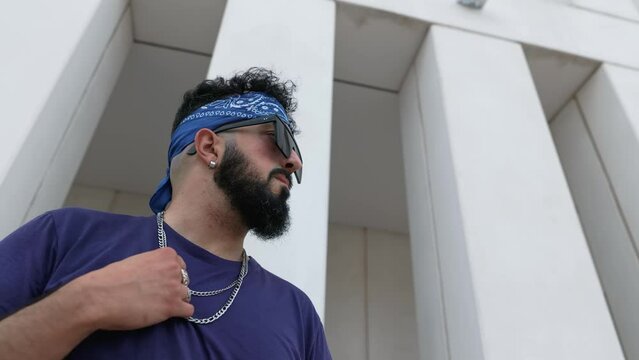 Low-angle pan shot of a stylish hip-hop male with attitude exuding swag representing urban culture and modern street style