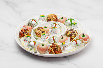 Close-up of different types of Indian sweets. Khoa Ladoo, Dryfruits Ladoo, on a white designer ceramic plate. Front view.