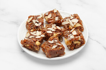 Close-up of Indian Dry fruits and nuts Barfi (sweet or mithai), on a white ceramic plate. Front view.