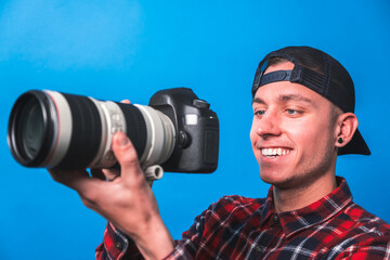 Happy photographer taking pictures checking his camera settings in a studio shooting as content creator