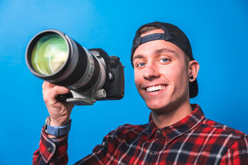 Happy photographer taking pictures covering his face with a camera with blank space for adds