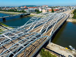 New triple tied-arc railroad bridge with four tracks over Vistula river in Krakow, Poland. Another bridge with cars and tram. Old town with Wawel castle in the background. Aerial drone view - 644939503