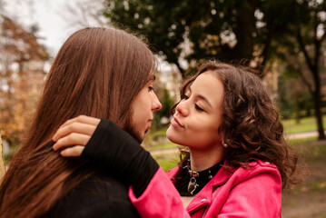 teenage couple of lovers with alternative look in a loving attitude looking into each other's eyes with complicity in a park during the fall