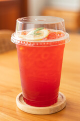 Close-up of tea mixed with lemon and soda in a plastic glass.