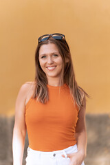 Portrait of a woman with sunglasses on head looking at camera and smiling while posing outdoors.