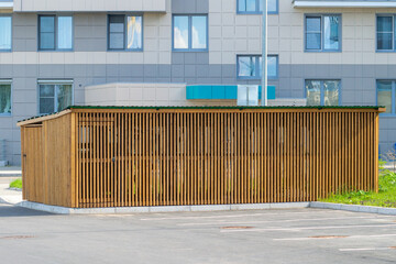 Dumpster containers hidden inside wooden cage in front of an apartment building