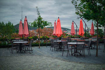Naklejka premium empty restaurant patio furniture view point in city park land outdoor environment space of cold autumn cloudy day