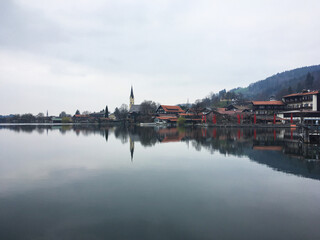 Scenic view of the town Schliersee reflected in eponymous lake against the cloudy sky, Bavaria, Germany, April 2019