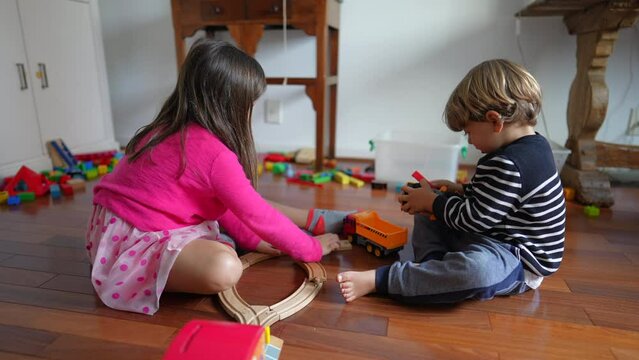 Child playing at home on floor, little boy and girl engrossed in play, siblings brother and sister sharing toys