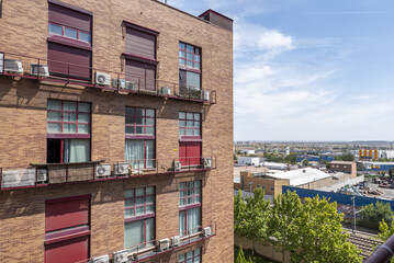 Facades of urban residential buildings next to an industrial estate on a sunny day