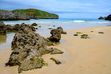 Obraz premium View on Playa de Borizo in Celorio, Green coast of Asturias, North Spain with sandy beaches, cliffs, hidden caves, green fields and mountains.