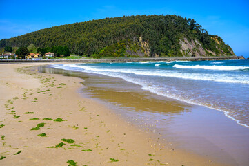 View on Playa de Ribadesella, Green coast of Asturias, North Spain with sandy beaches, cliffs, hidden caves, green fields and mountains.