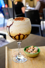 Glaass of iced frappuccino coffee with whipped cream, chocolate and ice cubes