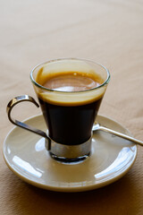 Small glass cup of black arabica coffee served in cafe, close up