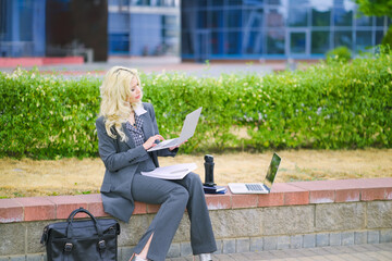 Fototapeta na wymiar Business woman in an office suit working outside with a laptop computer
